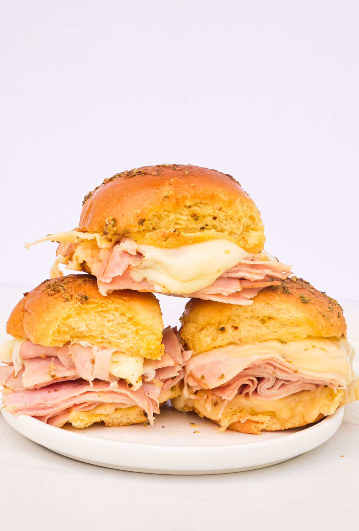 three sliders stacked in a pyramid shape on a white plate.