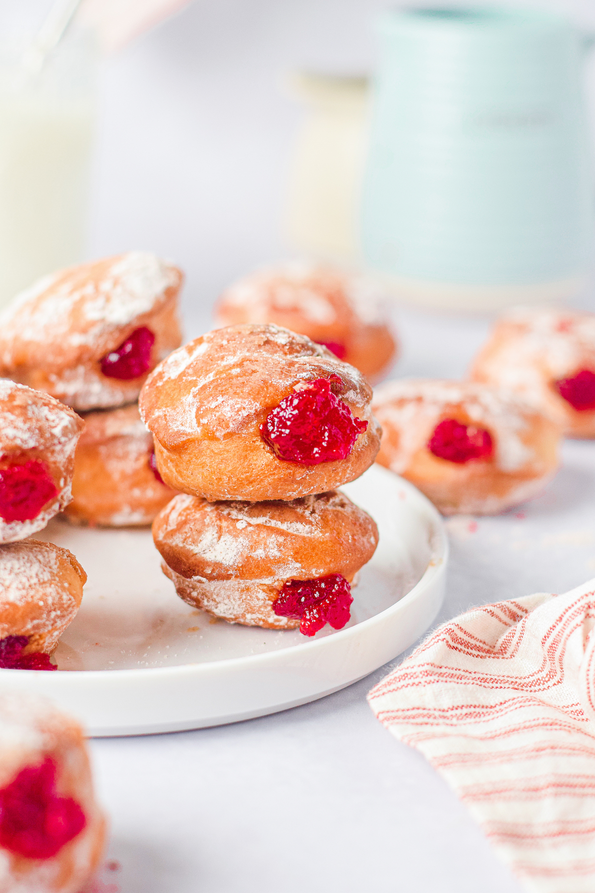 the jelly donuts stacked on a white plate.