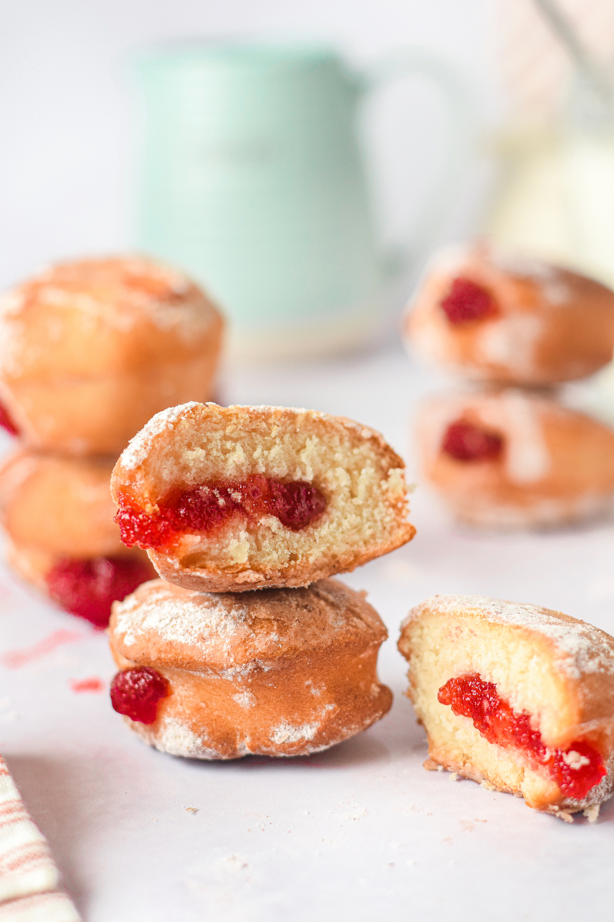 two air fried jelly donuts stacked vertically with one cut in half.