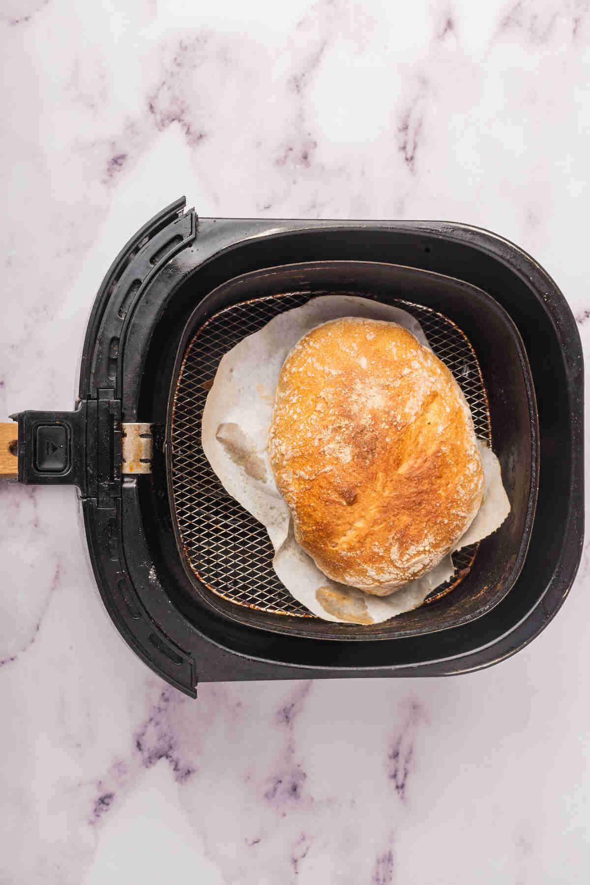 the baked bread loaf inside the air fryer basket.