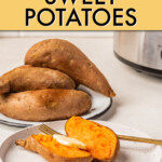 A sweet potato sliced in half with a pat of butter in front of a plate of whole sweet potatoes.