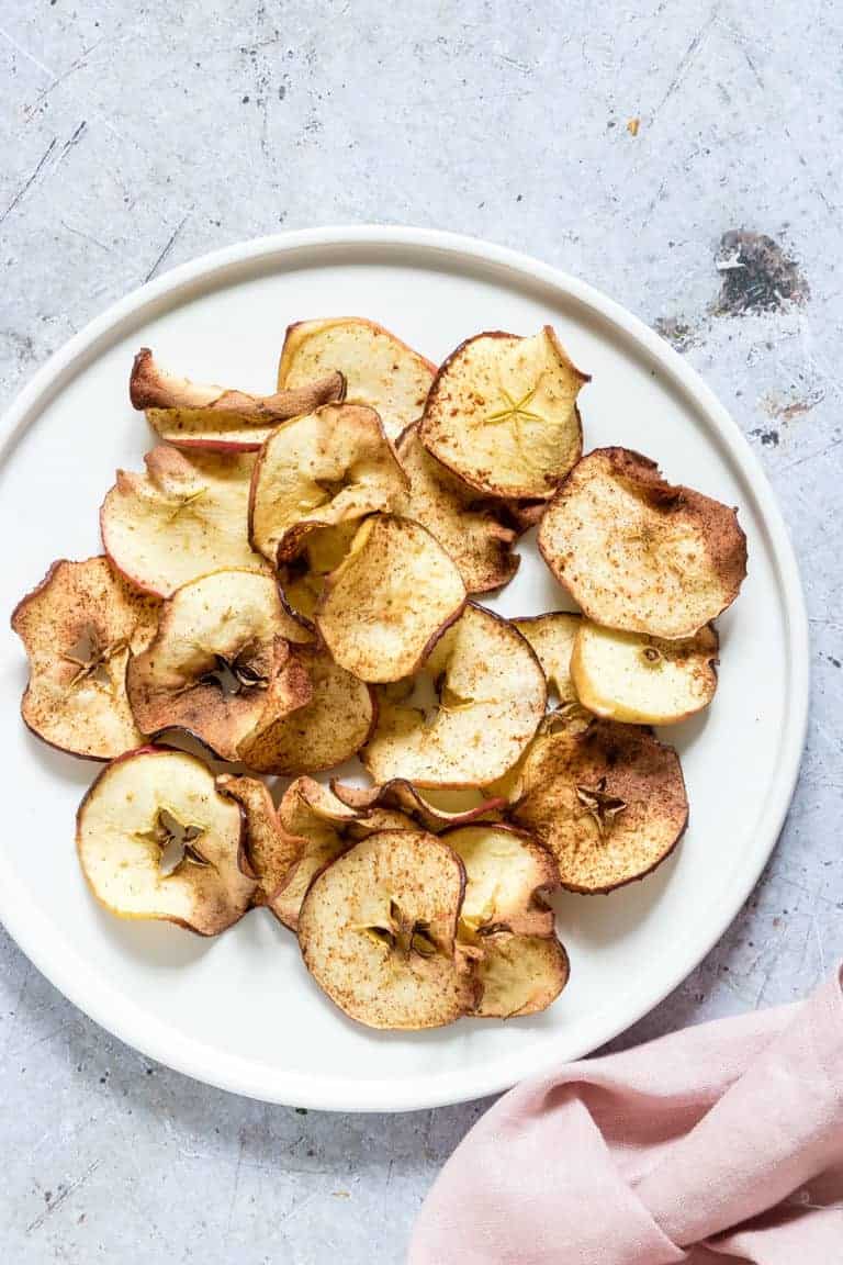 Air Fryer Apple Chips served on a white plate next to a pink cloth napkin