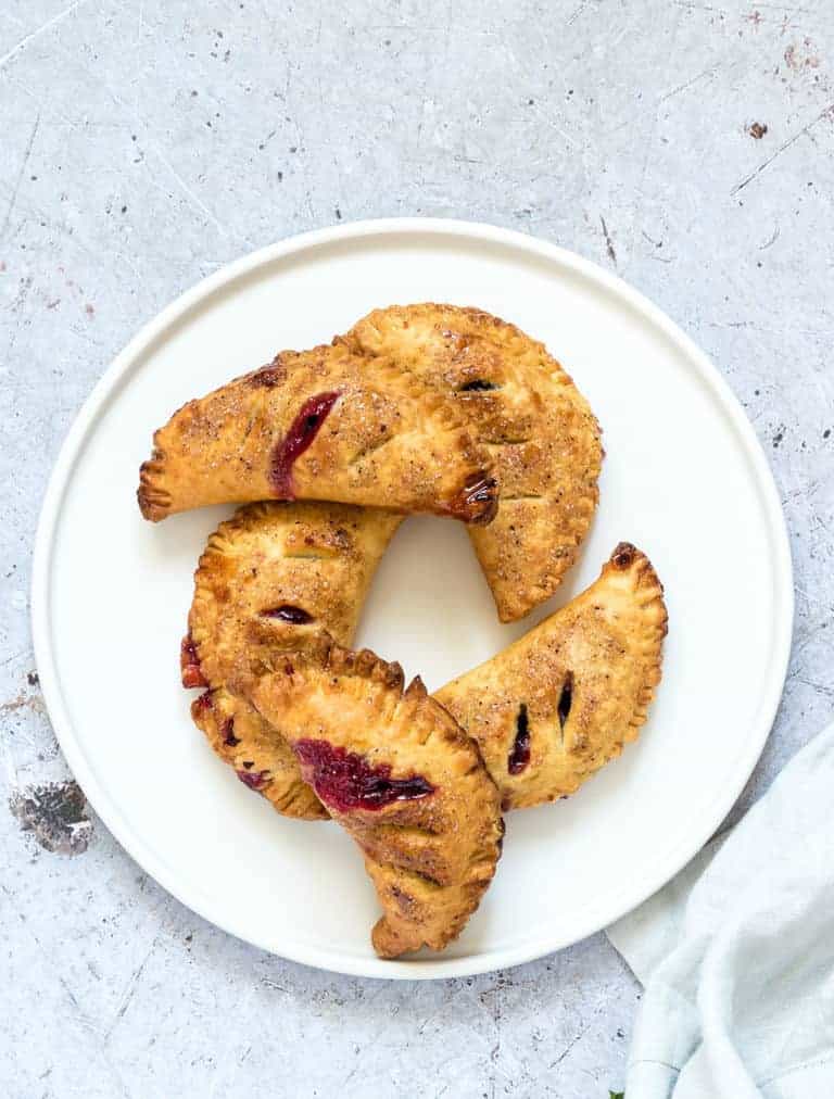 5 cooked air fryer blueberry hand pies on a white plate