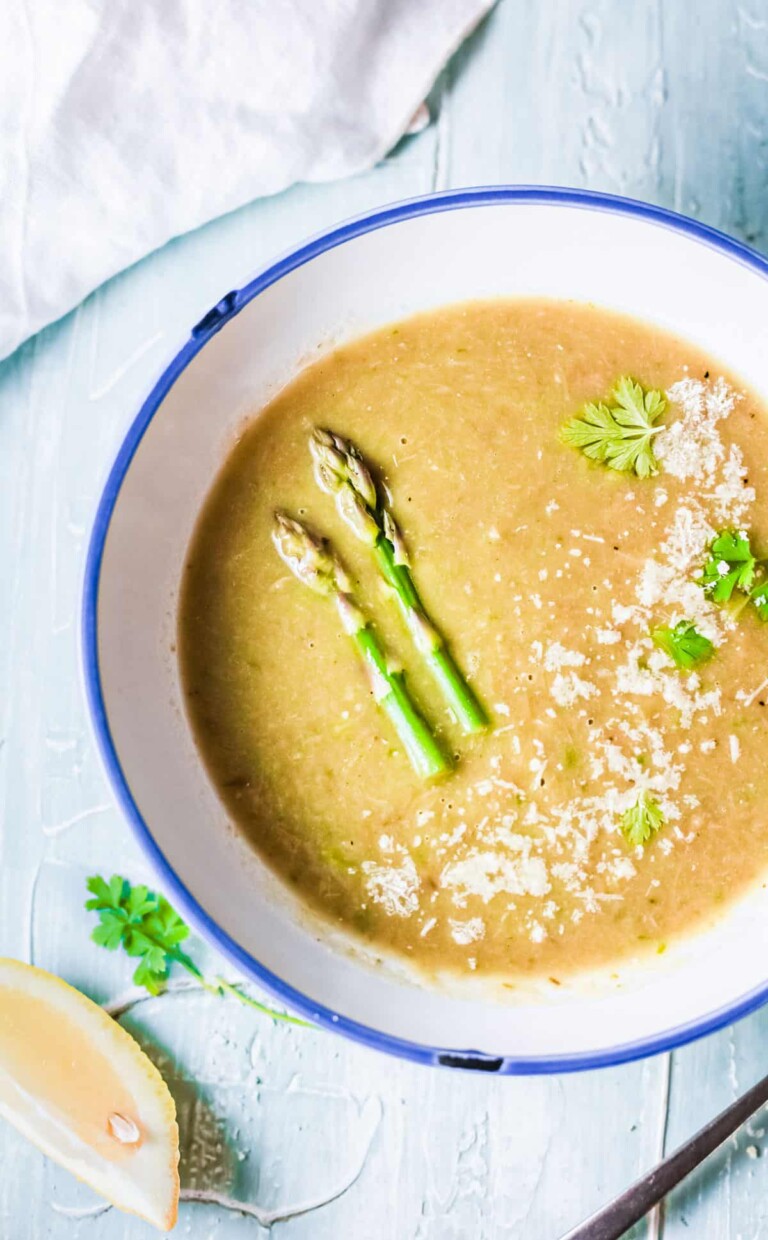 Asparagus soup in a white soup bowl with garnish.