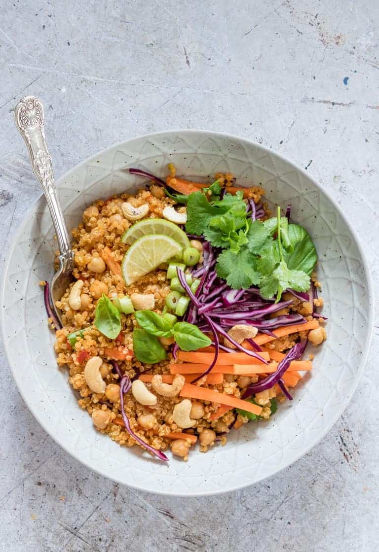 bowl filled with instant pot thai curry quinoa salad topped with lime wedges and toasted cashews