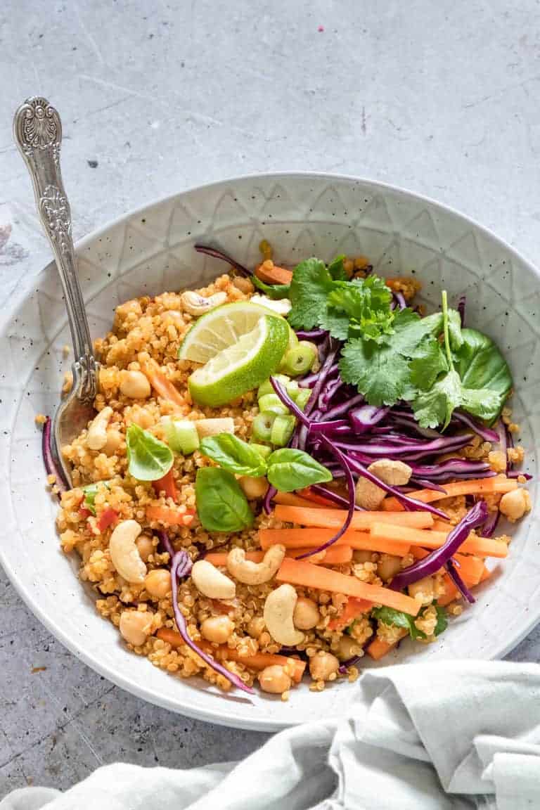 bowl of instant pot thai curry quinoa salad served with a spoon and cloth napkin