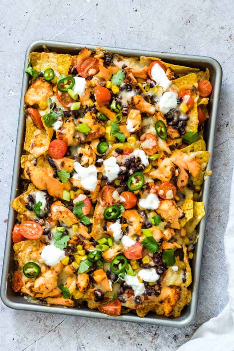 close up view of sheet pan filled with cooked salmon black bean nachos