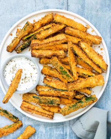 Air Fryer Zucchini Fries served with herbed yogurt dip on a white plate