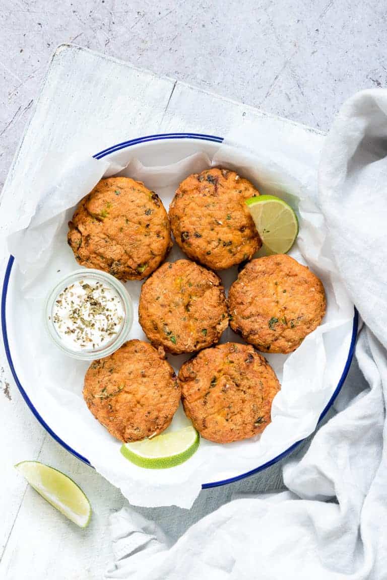 air fryer salmon patties served in a white bowl with lime wedges and dipping sauce
