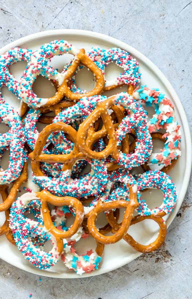 a plate filled with chocolate covered pretzels decorated with patriotic candy sprinkles