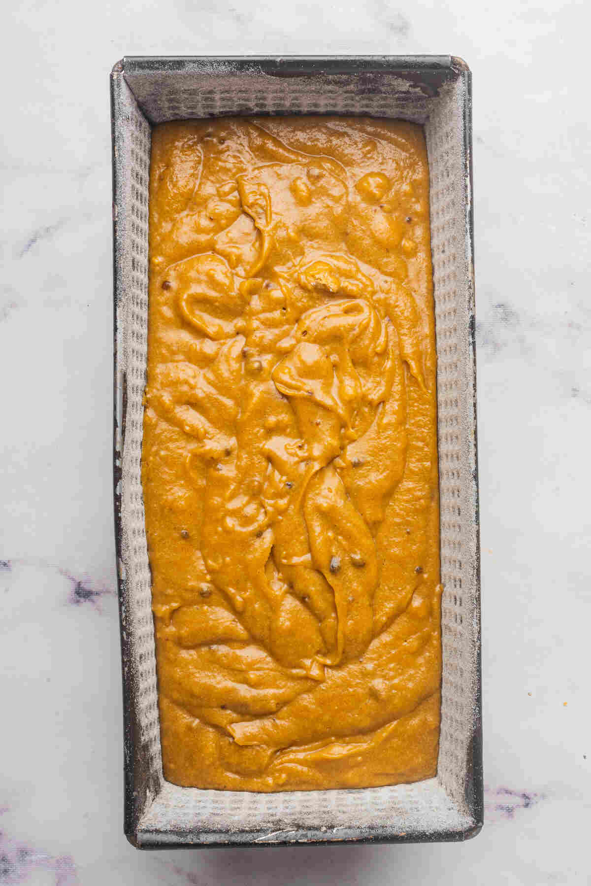 A loaf pan filled with bread batter, ready to be baked.