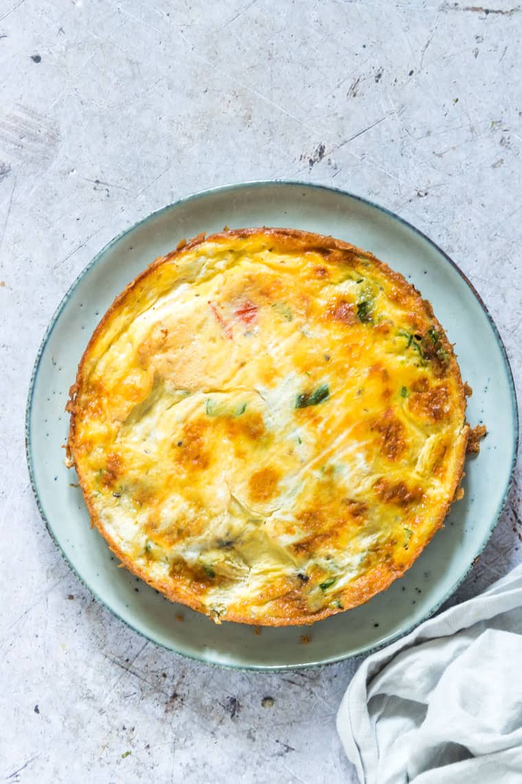 cooked breakfast frittata served on a blue ceramic plate