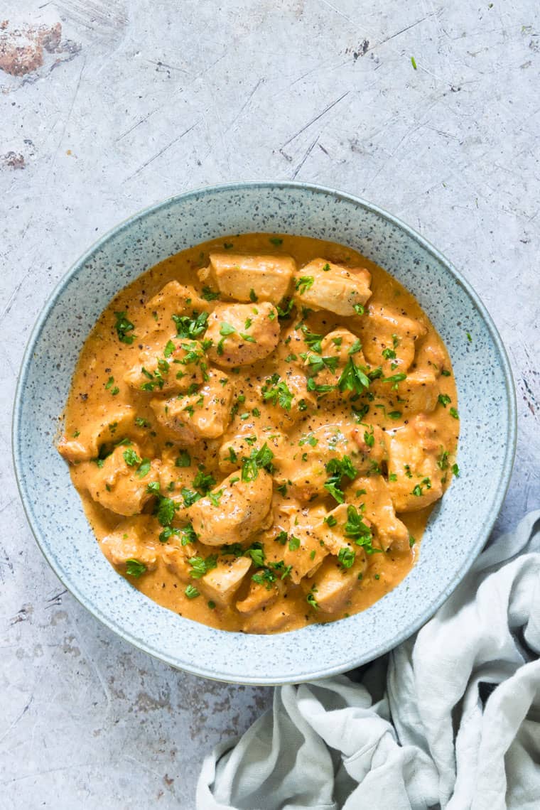 instant pot peanut chicken served in a blue bowl and garnished with parsley