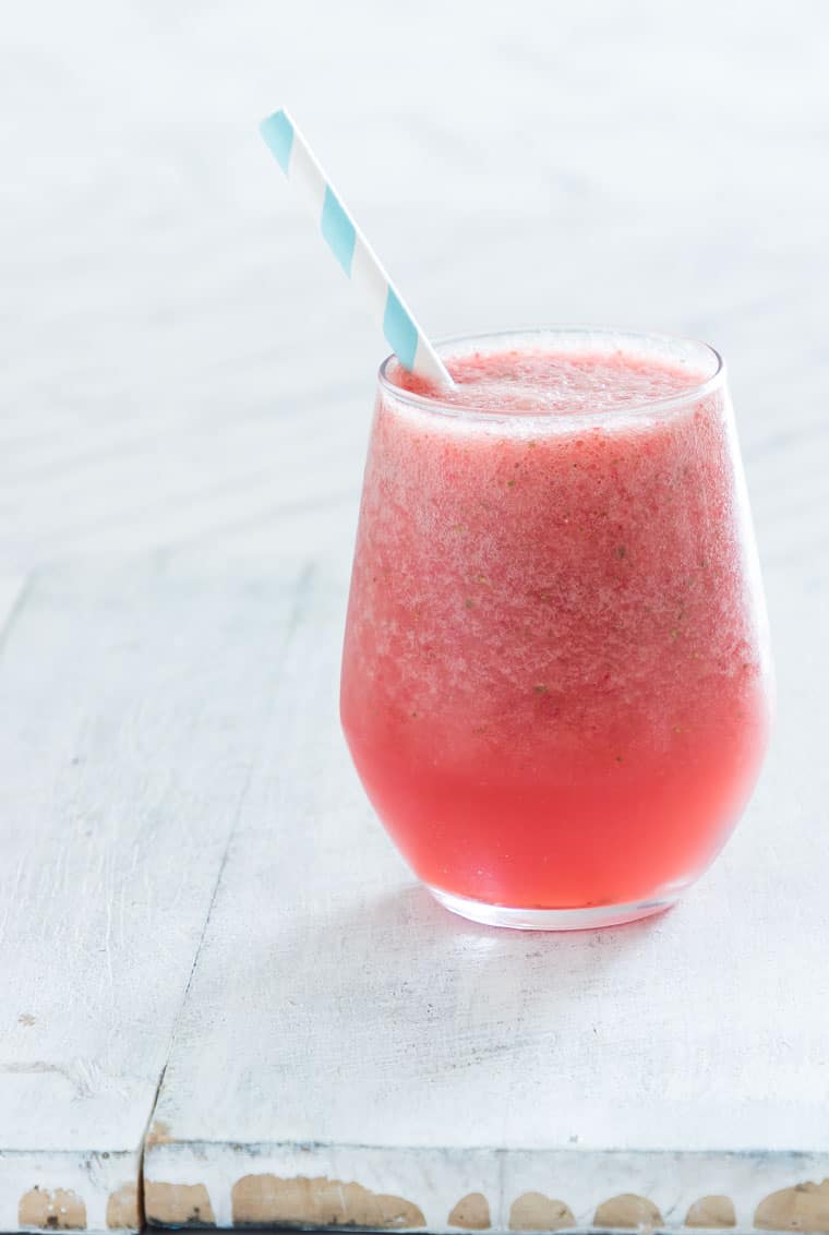 a glass of strawberry watermelon smoothie with a blue striped straw