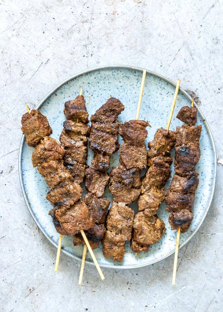 lamb skewers served on a blue plate