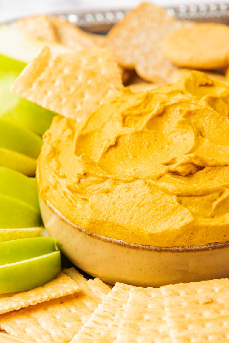 close up of pumpkin cheese cake dip with graham cracker diped in
