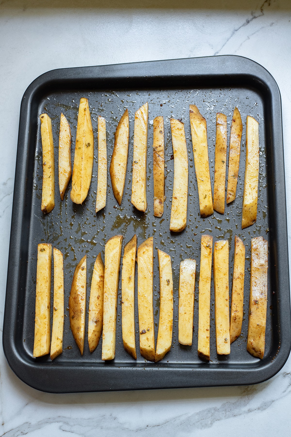 Sliced potatoes on a baking tray.