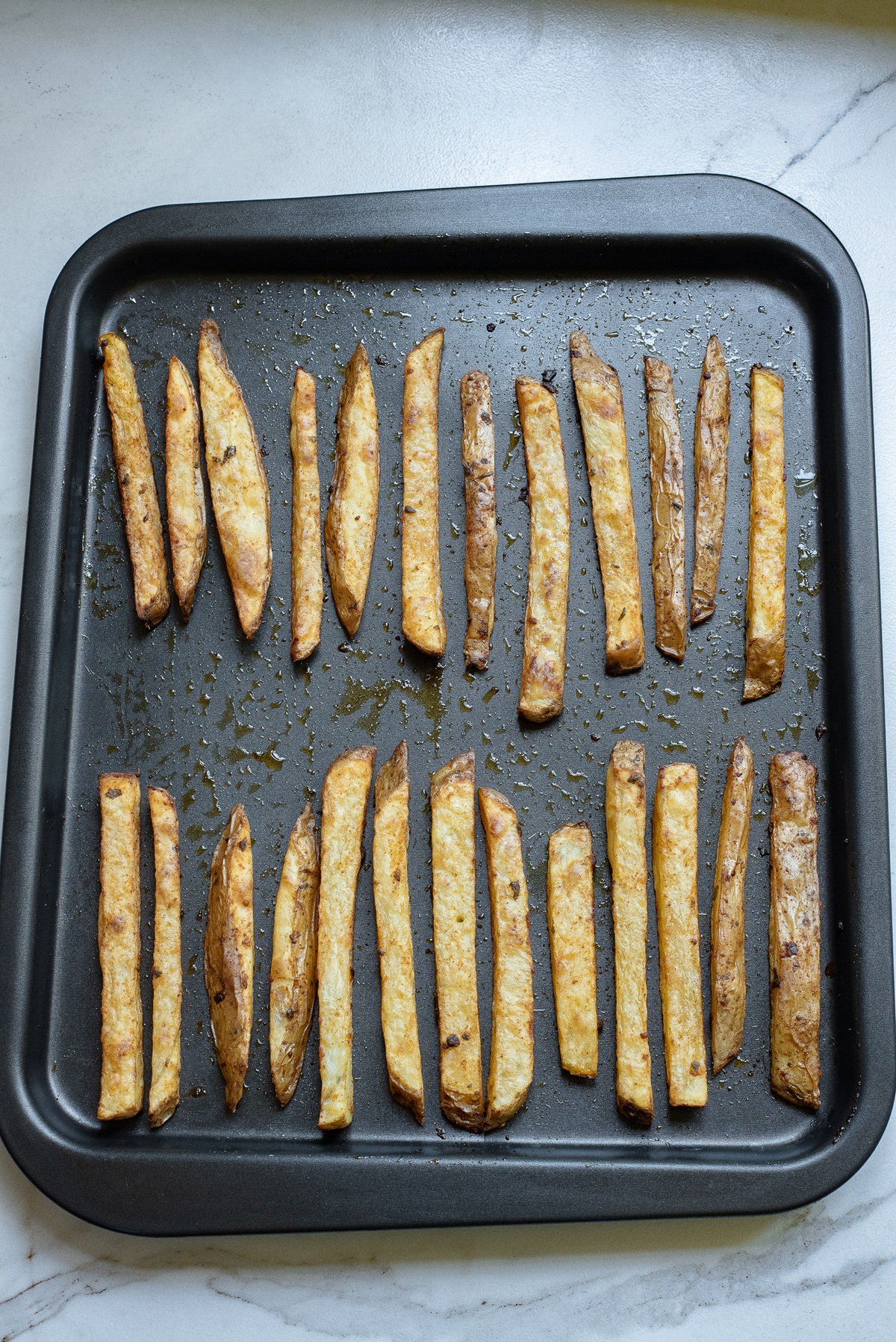 Sliced potatoes that have been baked on a baking tray.