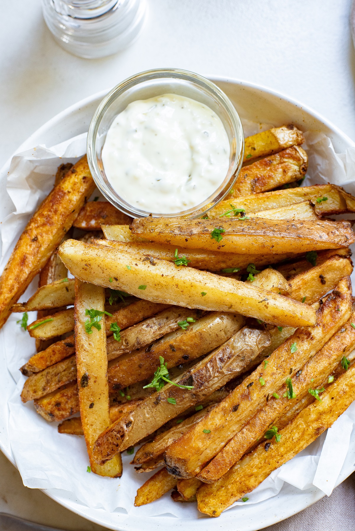 French fries in a bowl with white dipping sauce.