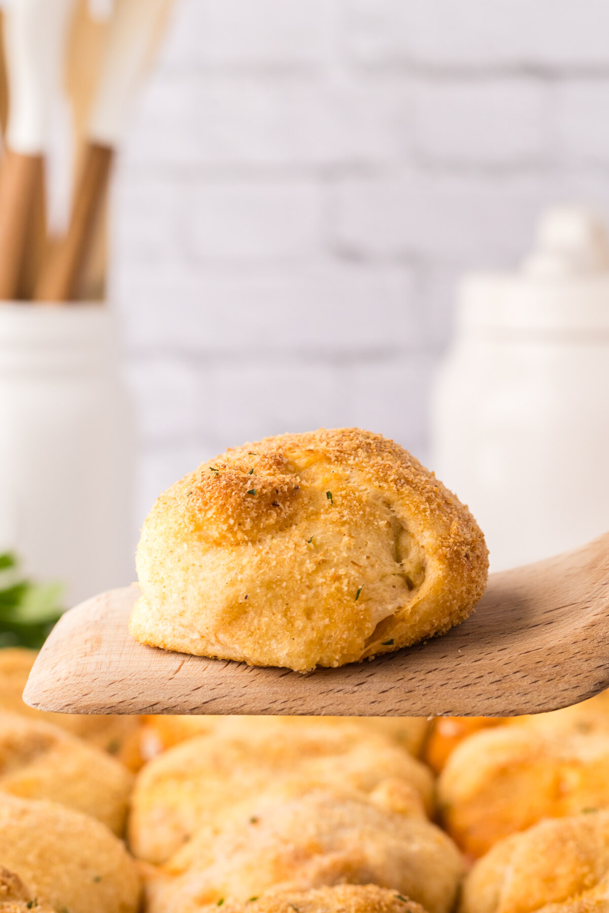 A single stuffed dough pocket being lifted with a wooden spatula.