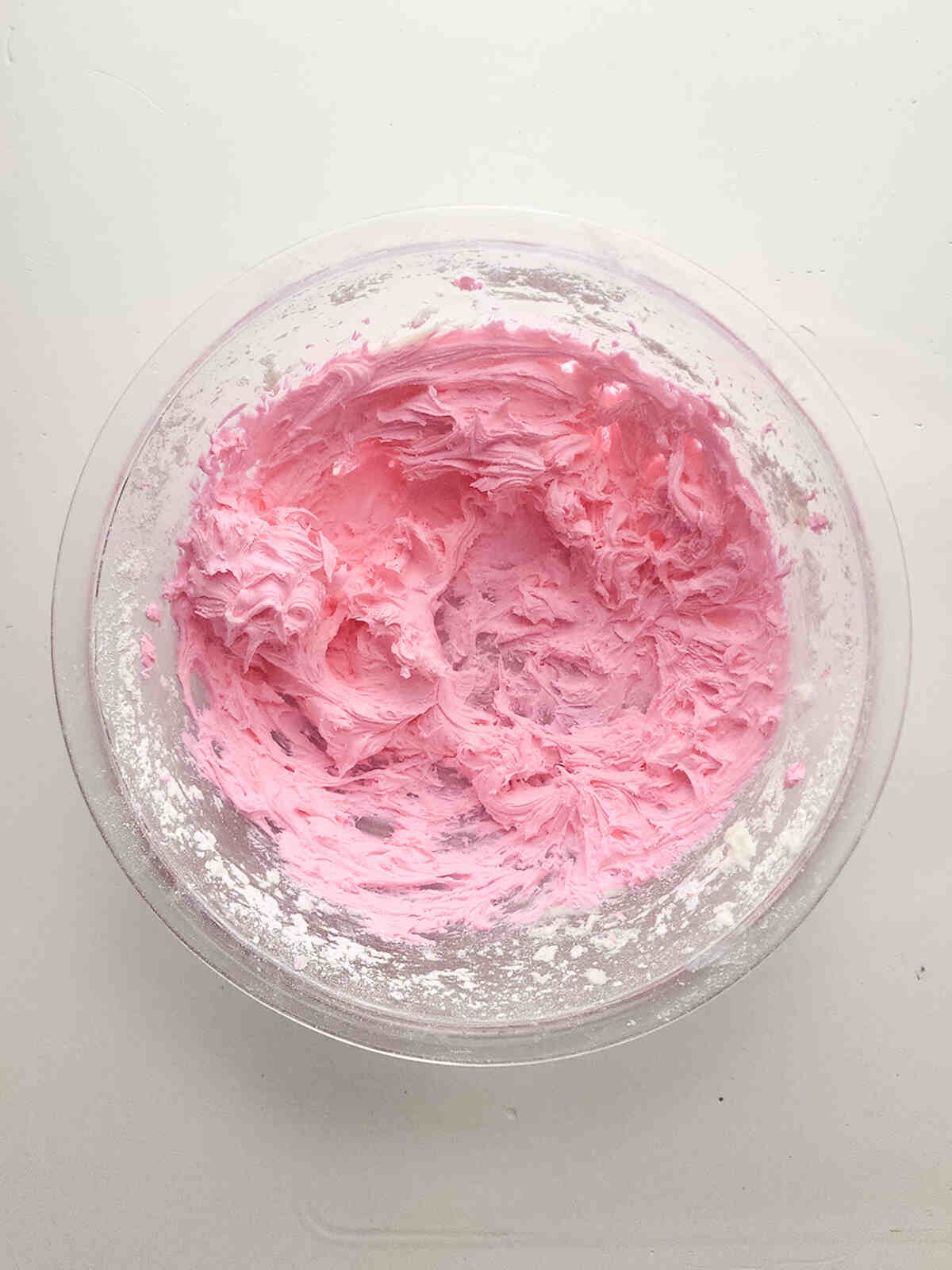 Pink frosting mixture in a mixing bowl.