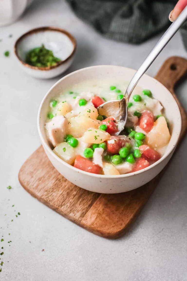 Slow cooker chicken pot pie in a white bowl with a silver spoon in it.
