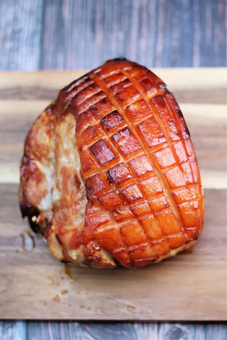 Slow cooker gammon glazed with maple syrup on a wooden board.