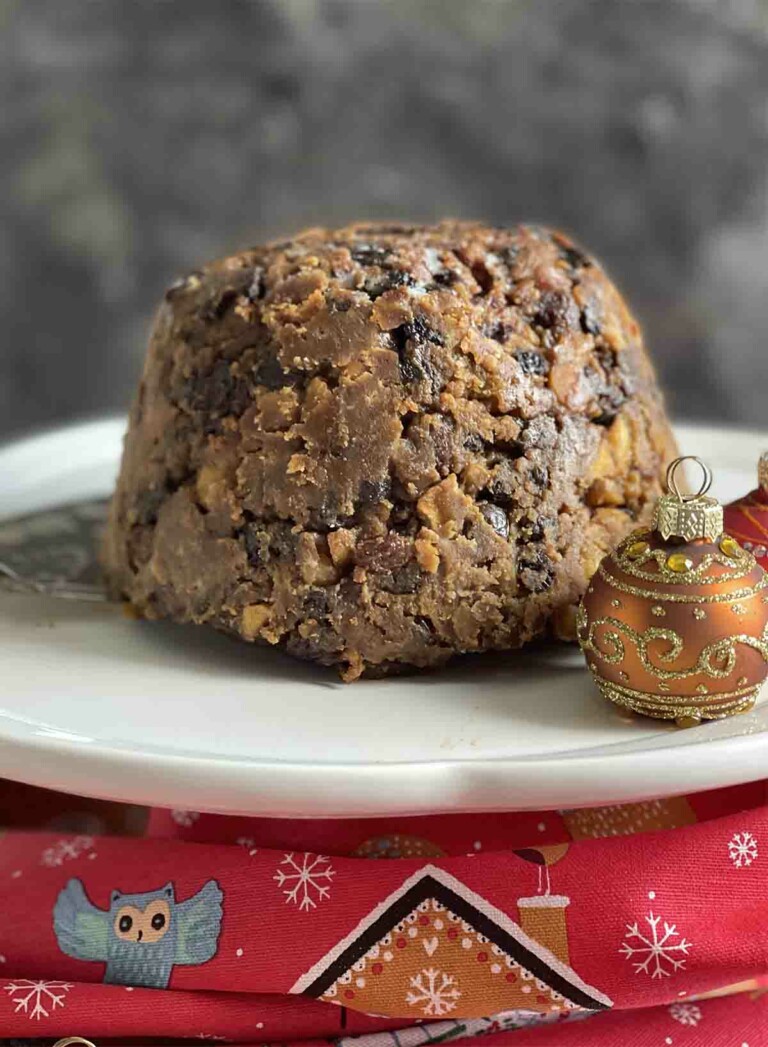 Slow Cooker Christmas pudding on a white plate with Christmas decorations.
