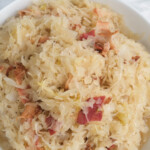 Close up view of sauerkraut with bacon bits in a white bowl