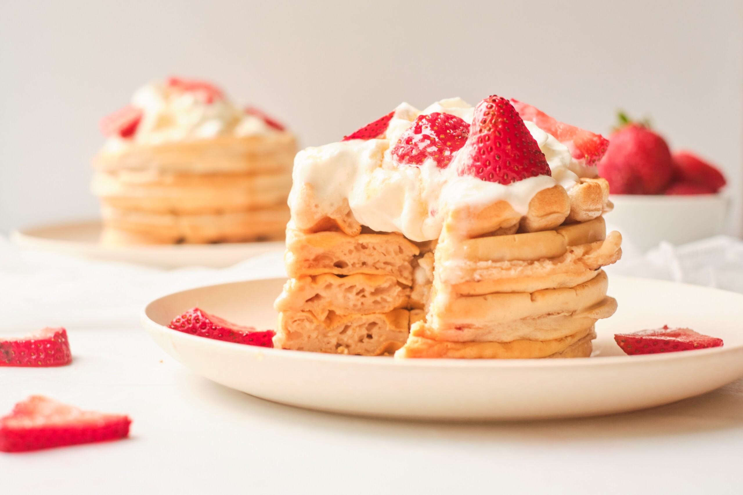 Centre view of a stacked waffle with strawberries and cream.