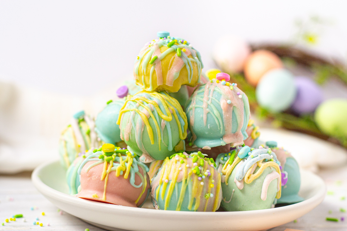 A stacked plate of pastel-colored Oreo truffles decorated with colorful drizzles and sprinkles.