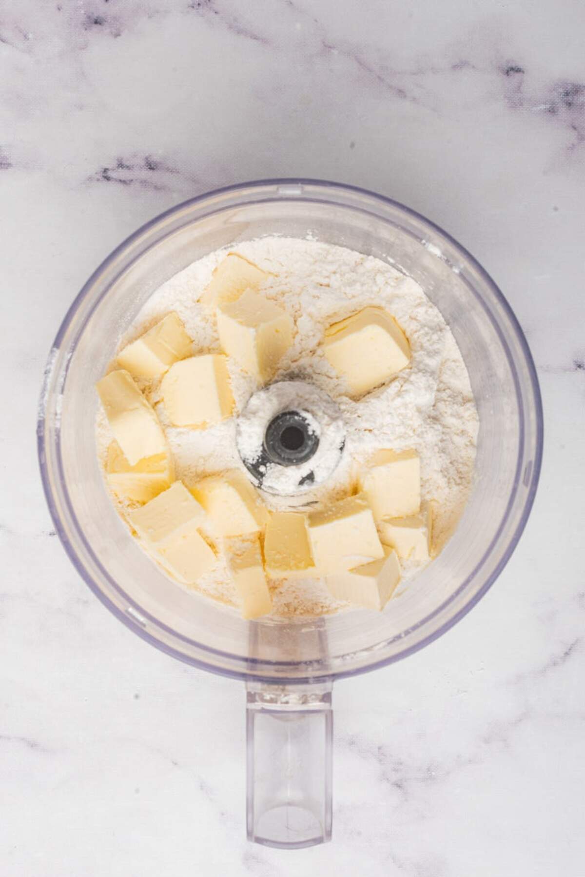 Cubes of butter added to the dry ingredients in a food processor for making pie crust.