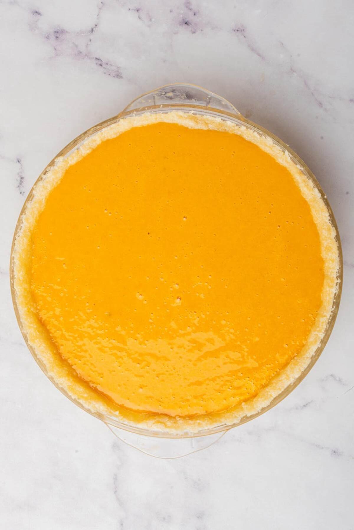 A filled pie crust with smooth pumpkin filling, ready for baking.