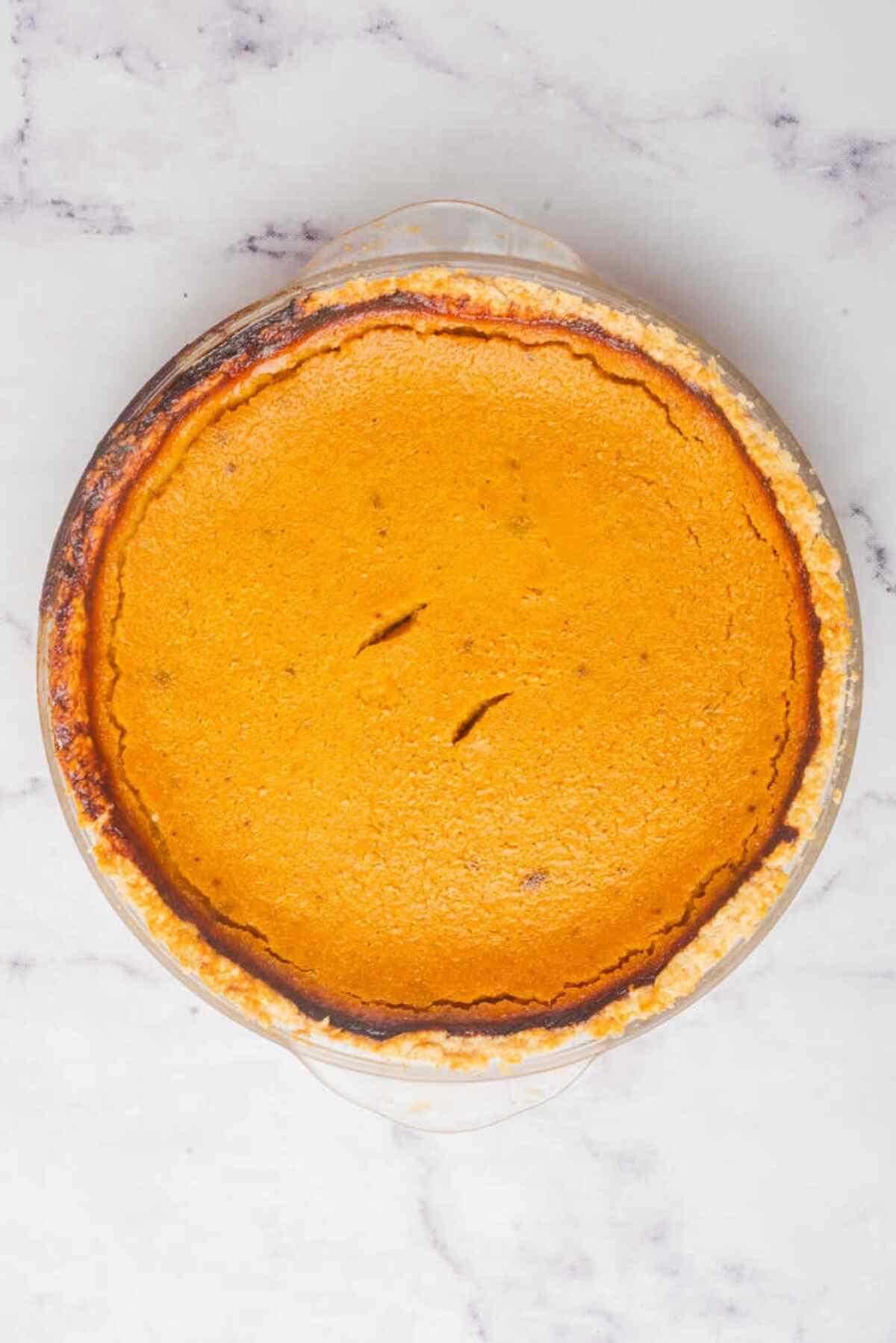 A freshly baked pumpkin pie with a slightly cracked surface, indicating it's ready to be served.