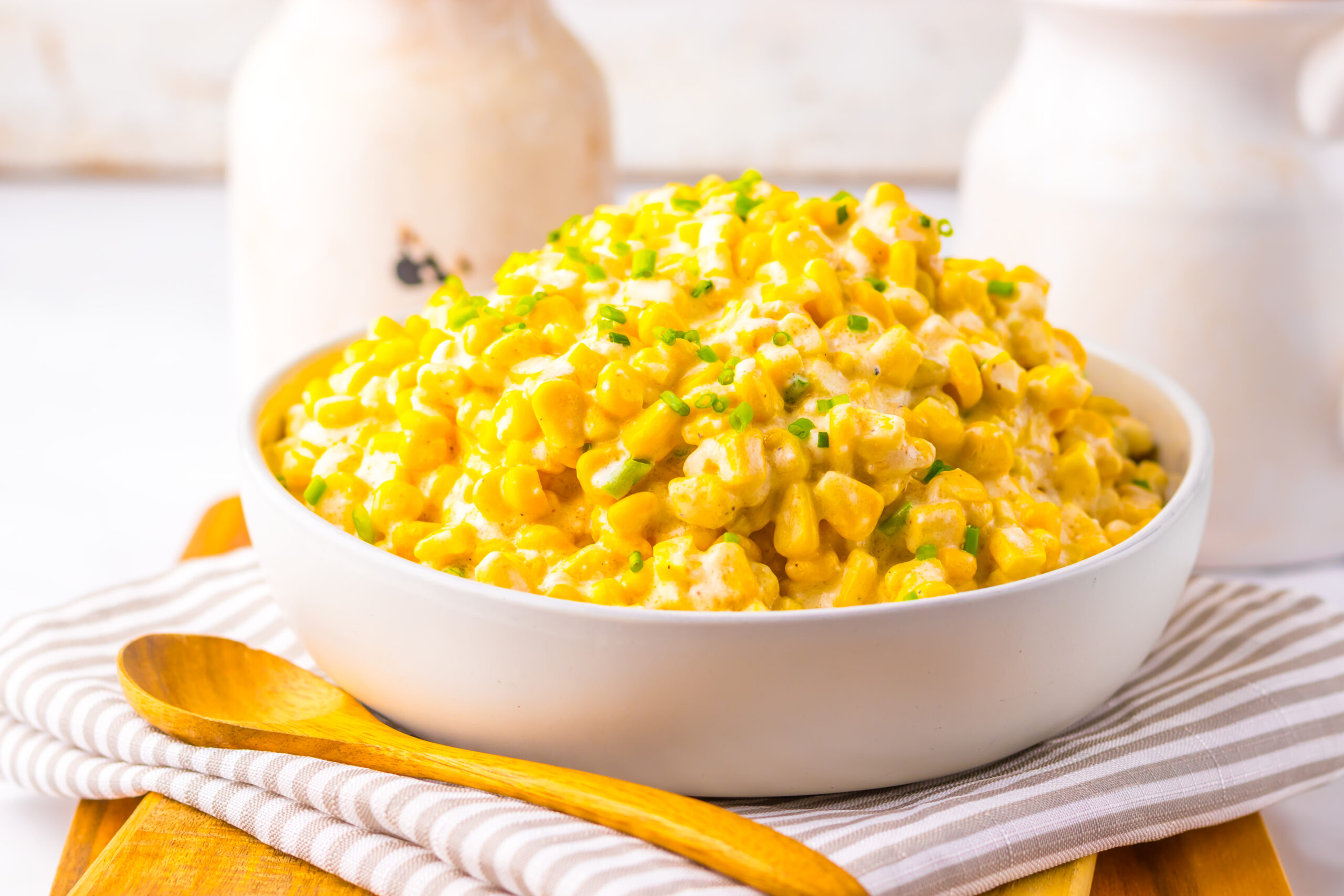 A bowl of creamed corn with a wooden spoon.