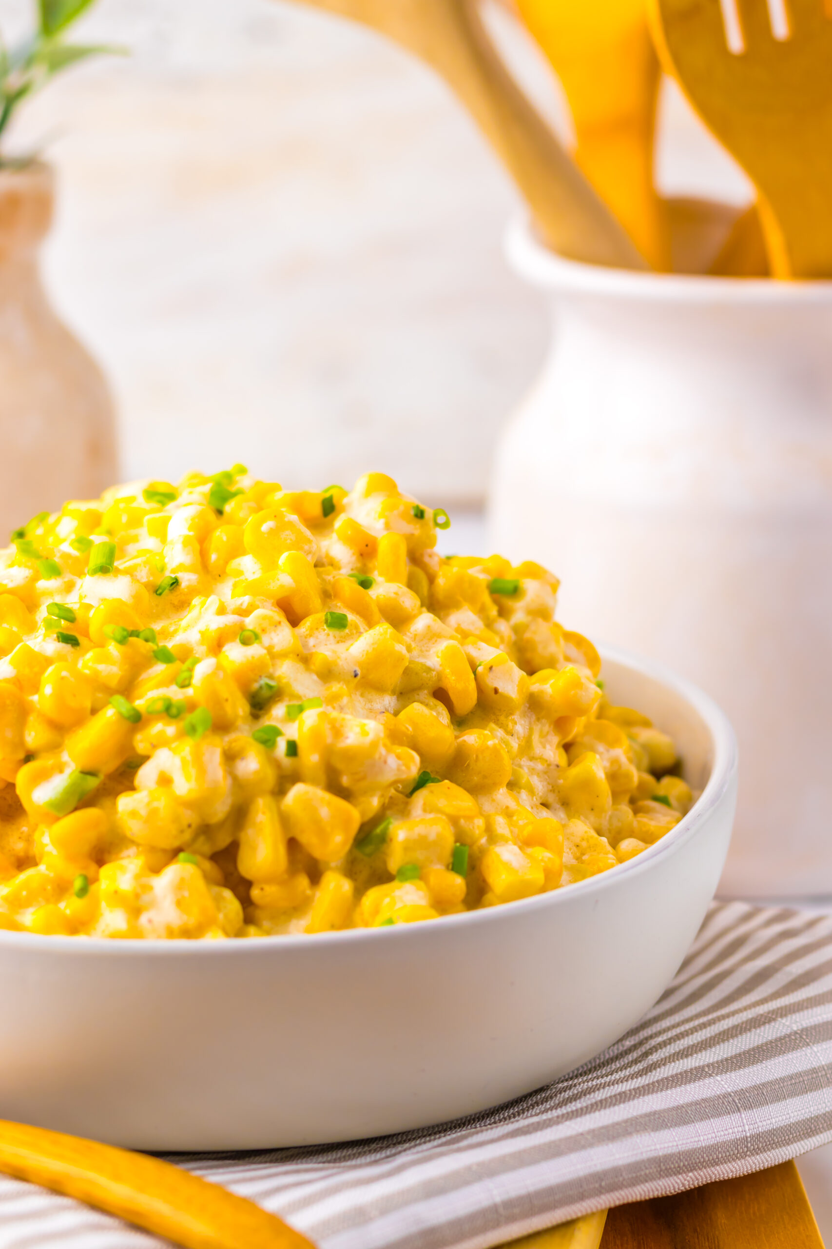 A bowl of creamed corn with a wooden spoon.