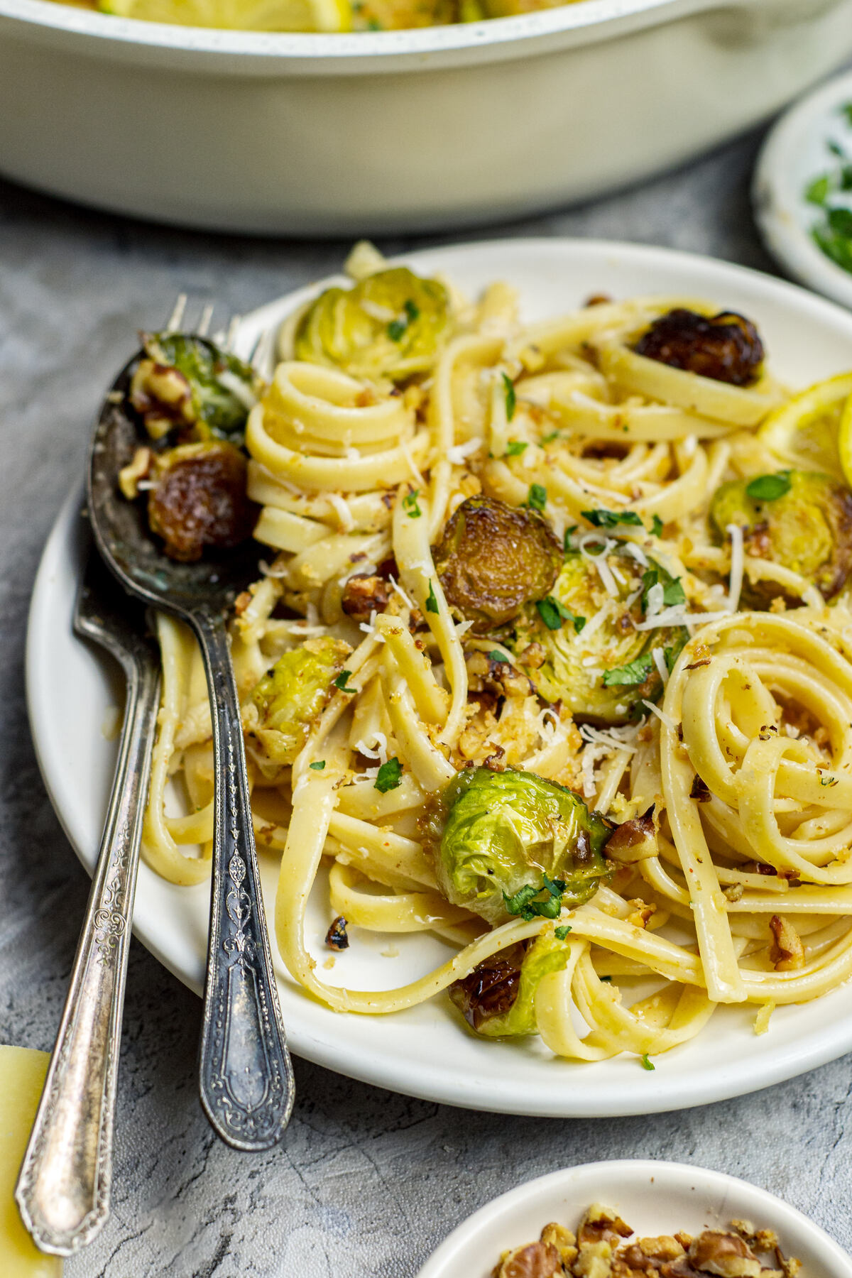 Plate of Brussels sprouts pasta with walnuts, cheese, and fresh parsley.