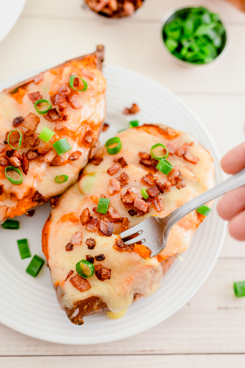 Baked sweet potatoes on a white plate with a fork.
