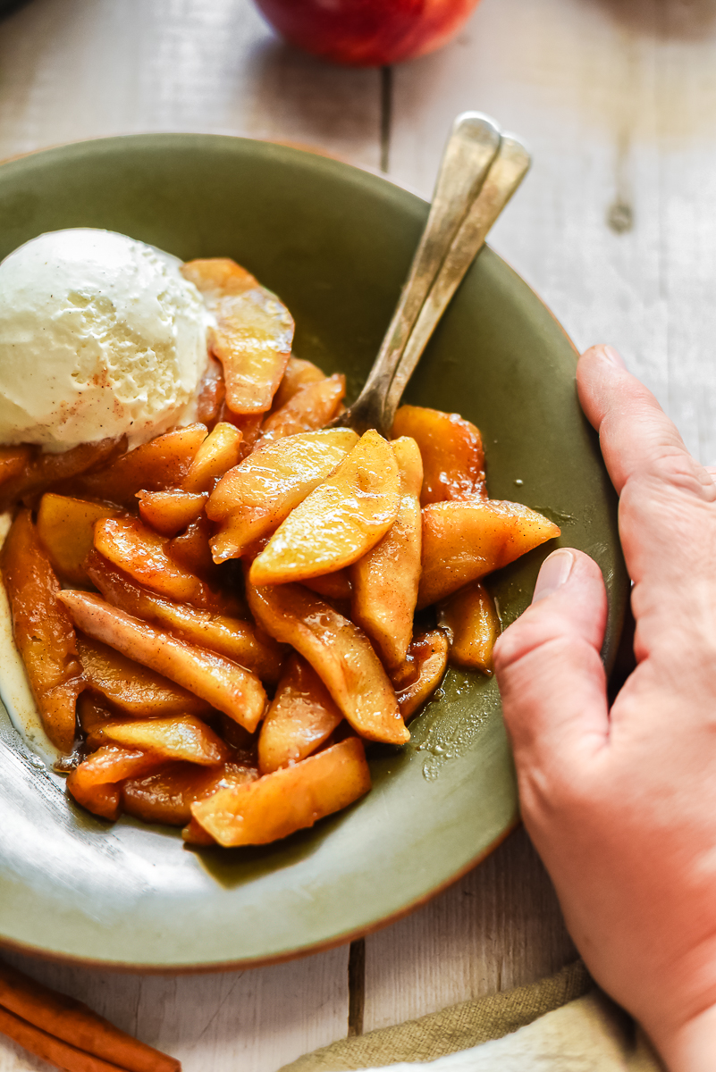 Fried apples in a green bowl with ice cream.